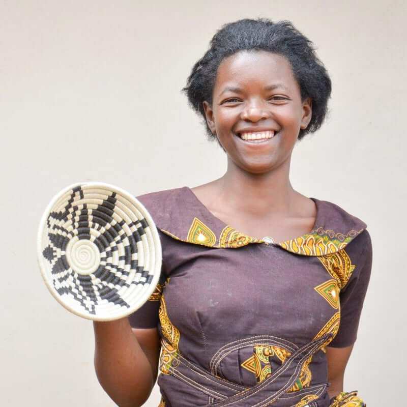 Rwandan Artisan Showing off handwoven wall plates
